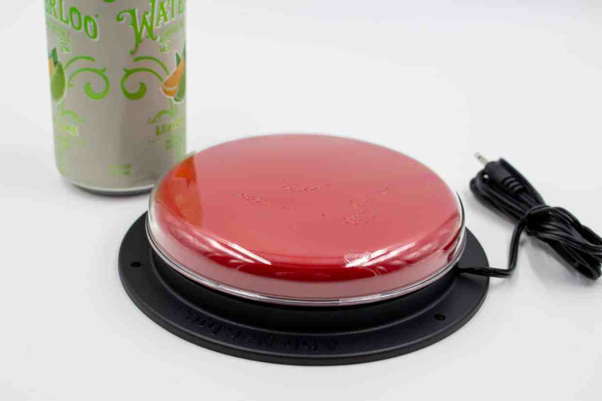 A large red button next to a soda can, the button is twice the diameter of the soda can.