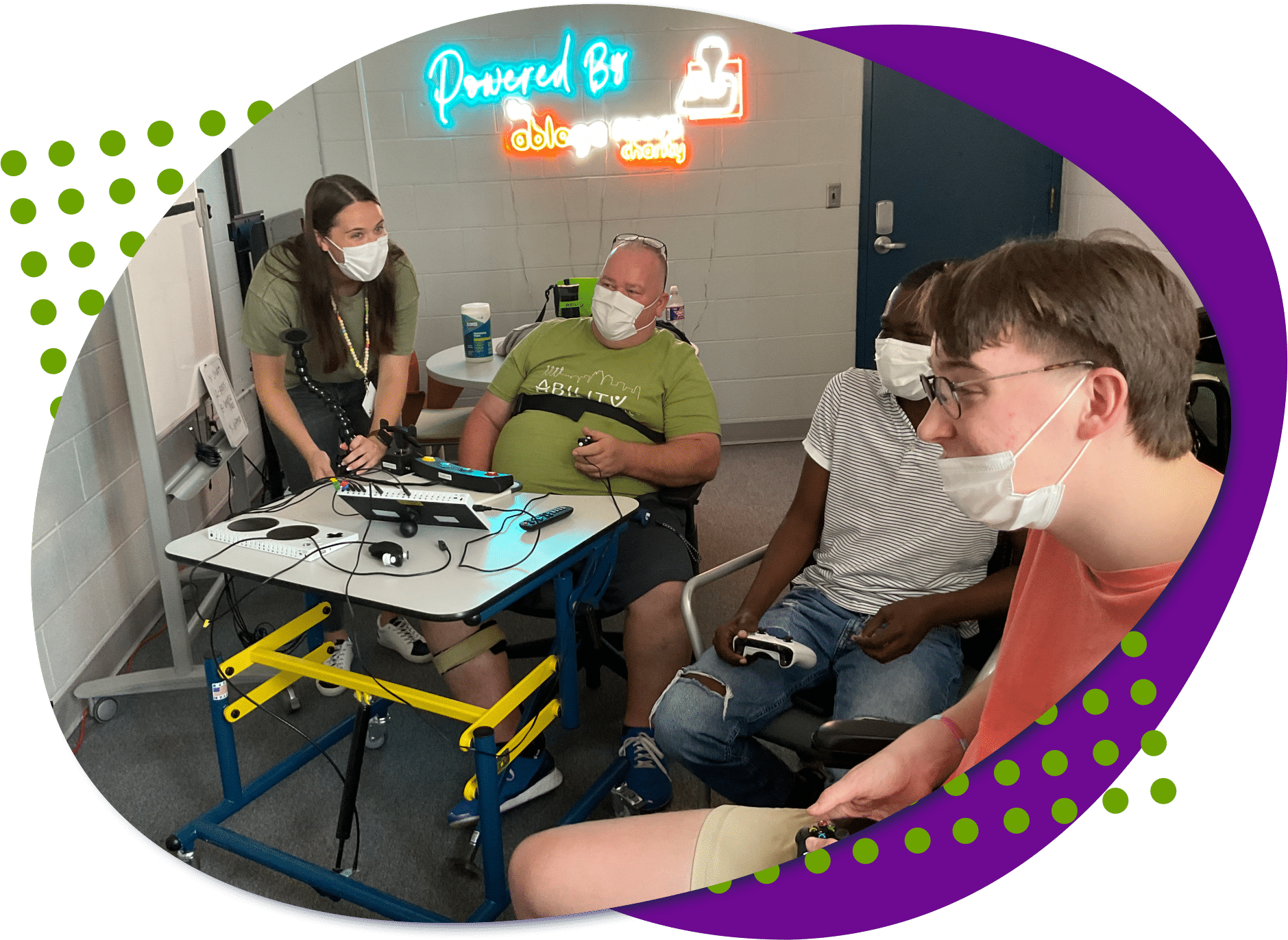 an image of four individuals, one standing leaning over and the other three individuals are sitting playing a video game together.