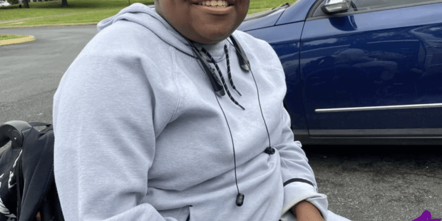 Carlito an African-American young man in his wheelchair outside his home. His mom's van in the background.