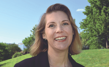 a woman smiling trees and green hillside in the background