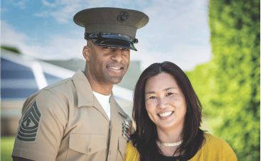 A man and woman, the man is wearing a tan military uniform with a matching cap the woman is wearing a yellow sweater