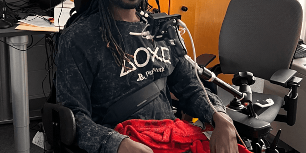 A photo of Damion with his adaptive gaming equipment, the QuadStick ready to game and socialize with friends.