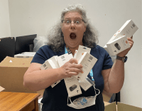 Texas Technology Access Program staff member holding several boxes of switches with a funny shocked and surprised look on her face