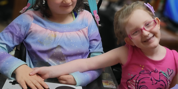 A picture of Jolee with her new gaming setup her sister is standing beside her