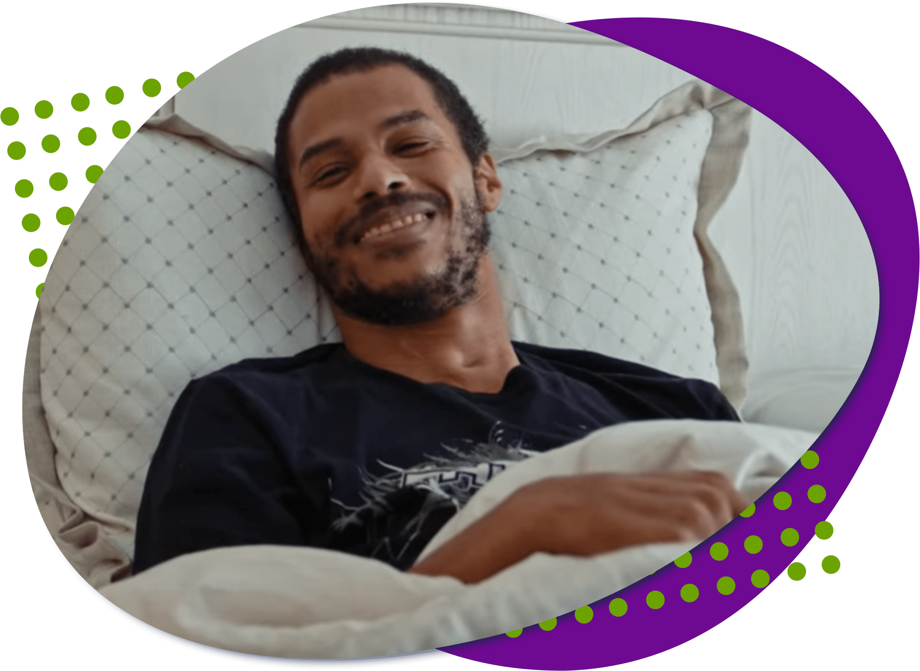 Jose, a young man with a light beard in bed smiling at the camera.