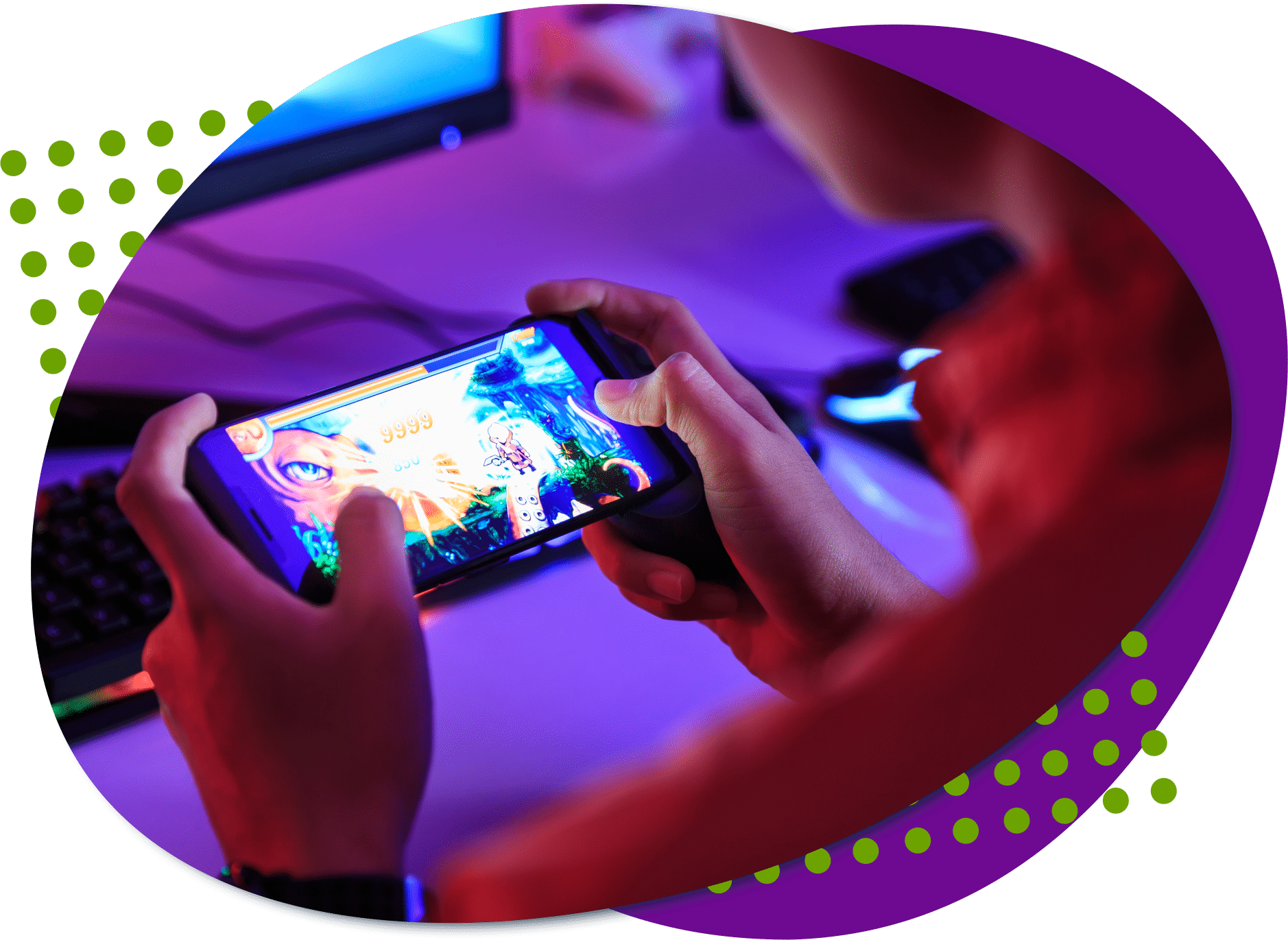 An photo taken from behind an individual who is sitting holding a phone playing a video game. A computer screen and keyboard are in front of the individual.