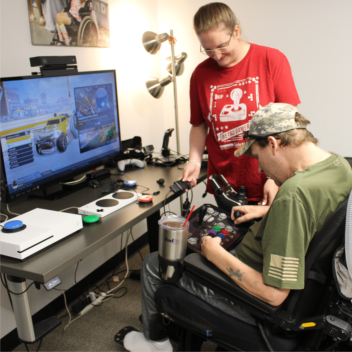AbleGamers Peer Counselor working with a young man who is using a wheelchair to find the right set up to game. Support peer counseling, host a fundraiser!