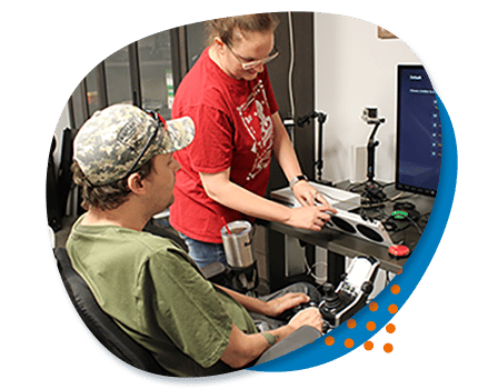 AbleGamers Peer Counselor Jessie showing a young man how to set up an xBox adaptive controller during a peer counseling session