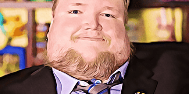 a photo of Steven Spohn wearing a smile and a suit with a gray tie with stripes and an Ablegamers controller pin on his lapel