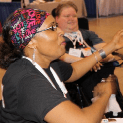 woman playing a woman having a lot of fun playing video games Steve Spohn is in the background watching